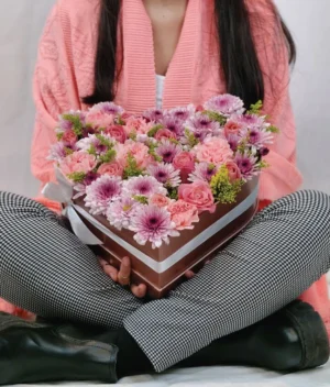 mujer con arreglo en forma de corazón con flores rosas