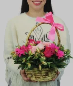 mujer con canasta de flores rosas