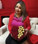 mujer con arreglo de corazón con rosas rojas y ferreros